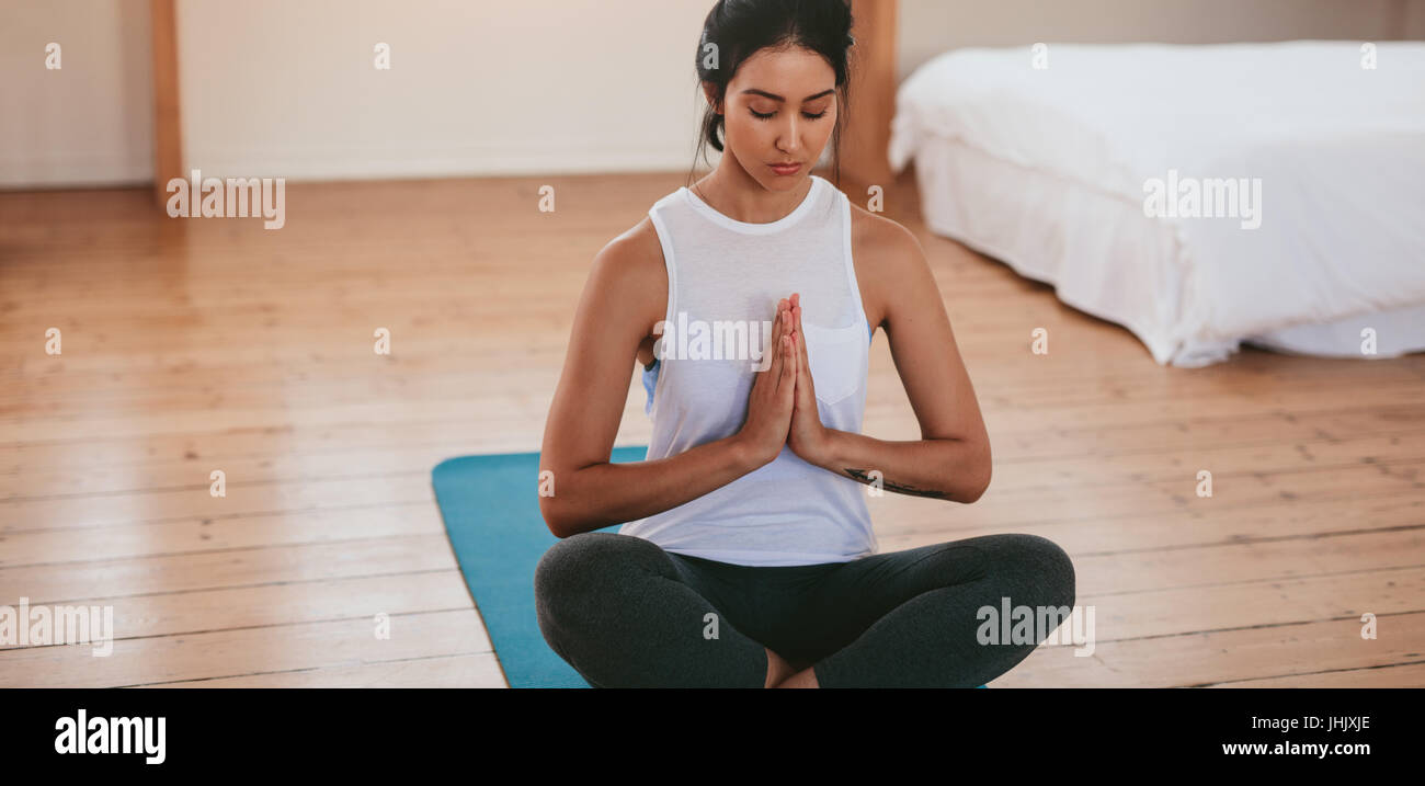 Porträt von attraktiven jungen Frau zu Hause trainieren Yoga Übung auf Matte. Fitness-Frau meditieren im Lotus Pose. Stockfoto