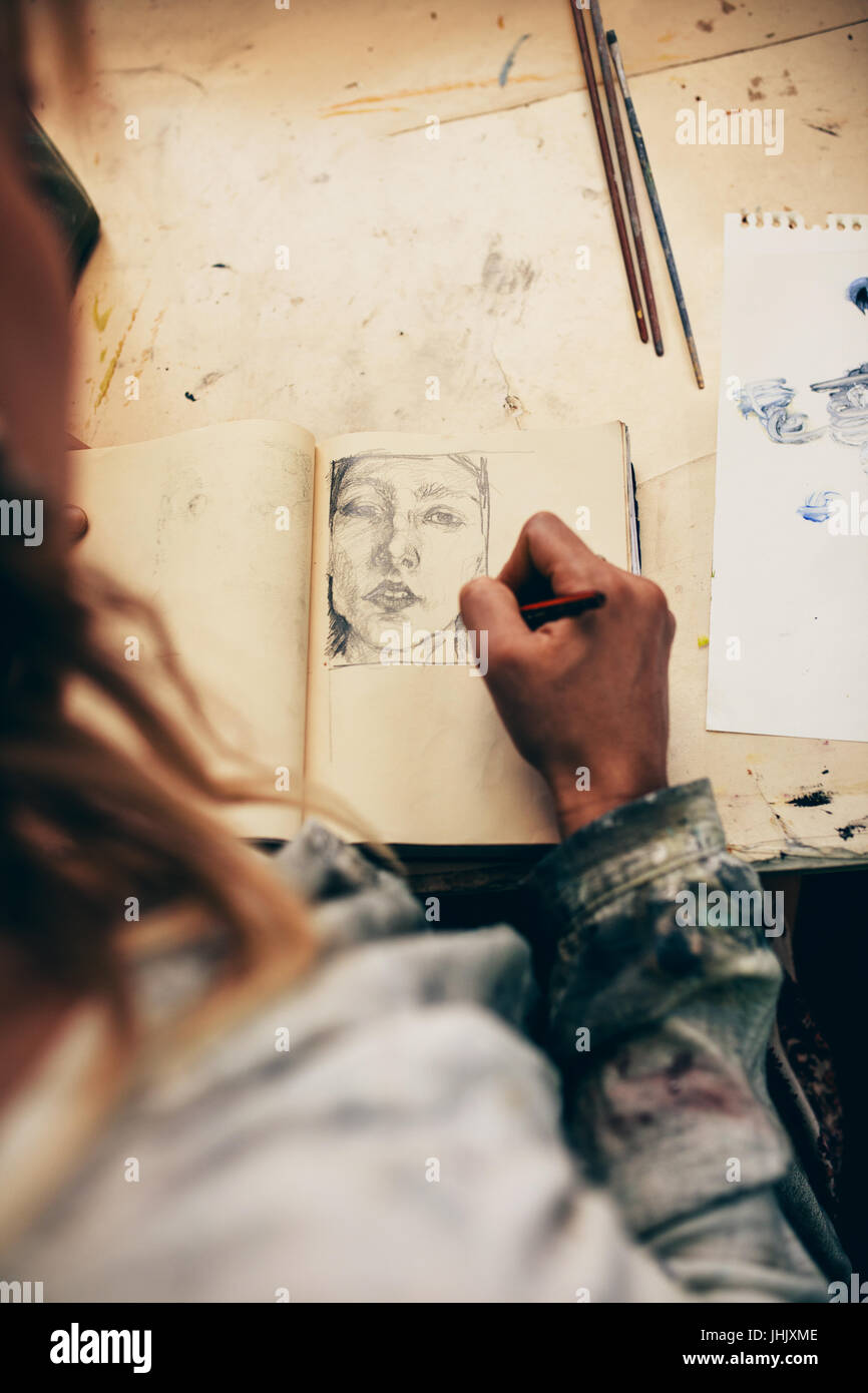 Draufsicht der Künstlerin Skizzieren auf Buch in ihrem Atelier. Nahaufnahme der Malerin in ihrem Atelier arbeiten. Stockfoto