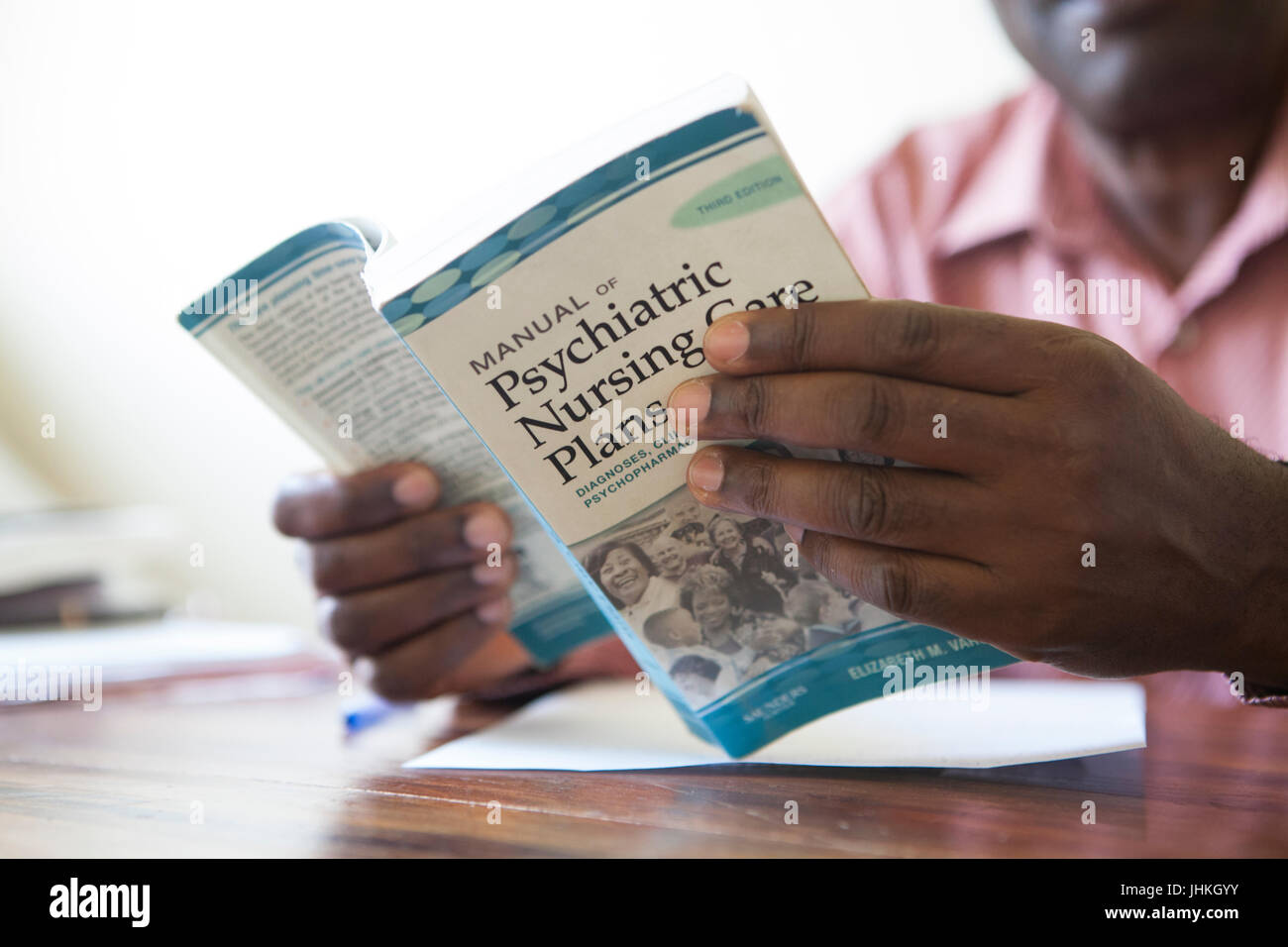 Ein Mann durch ein Buch über Pyschiatric Krankenpflege, Uganda. Stockfoto
