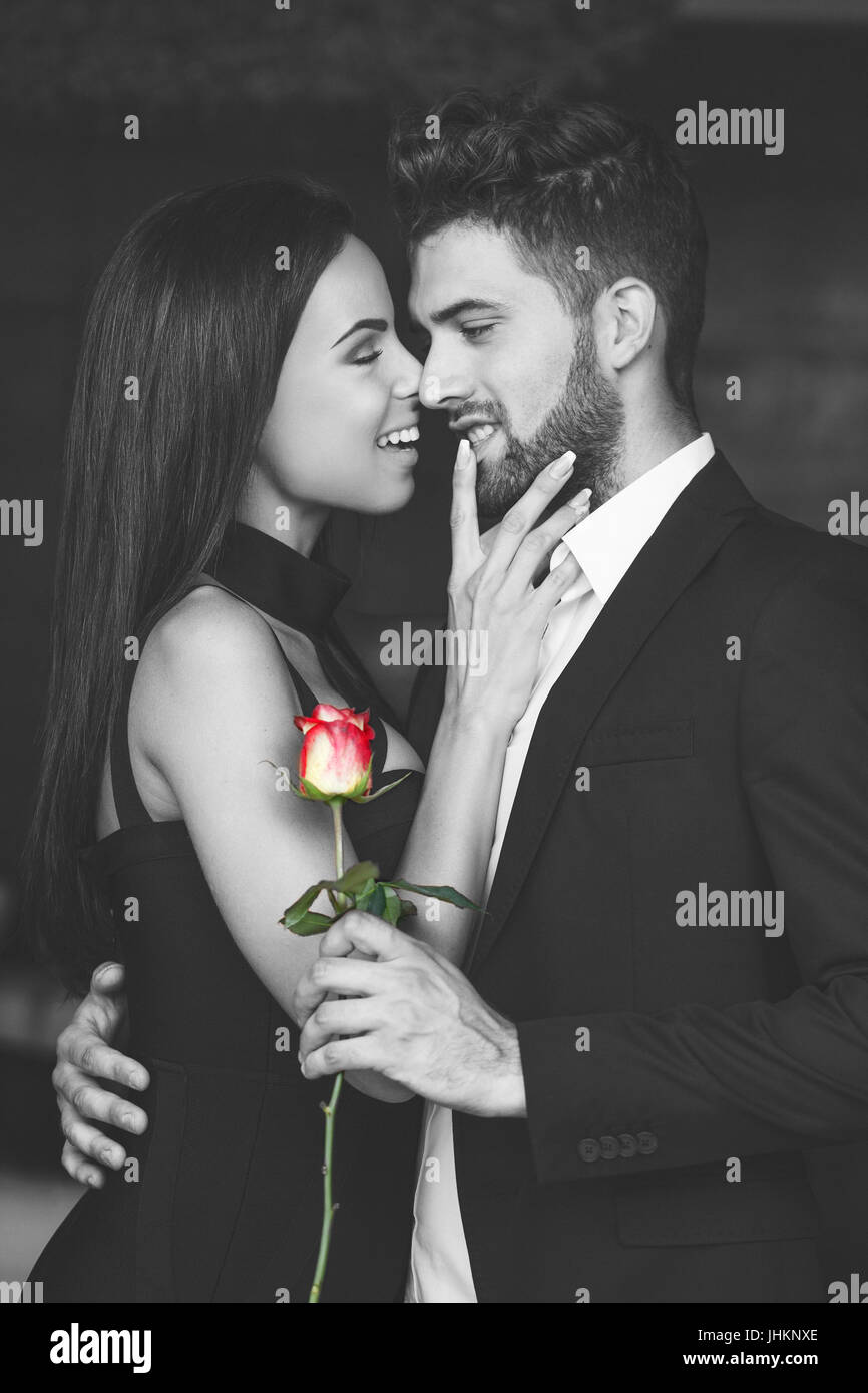 Glückliche junge verspielte Paar schwarz und weiß mit roter Rose, Liebe, selektive Färbung Stockfoto