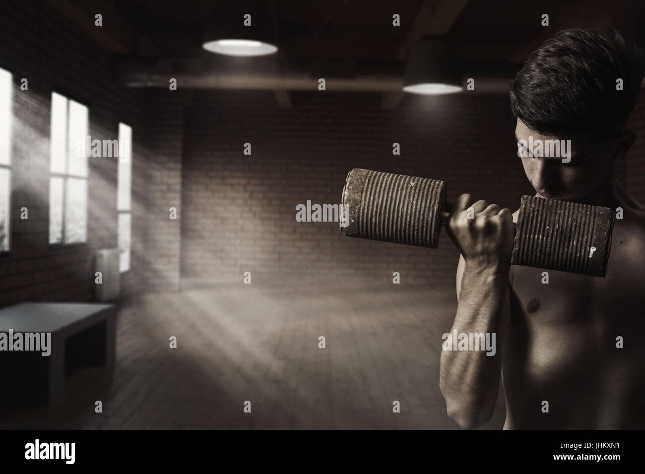 sportliche junge Bodybuilder Übungen mit rostigen Hantel vor Ziegel Halle Stockfoto