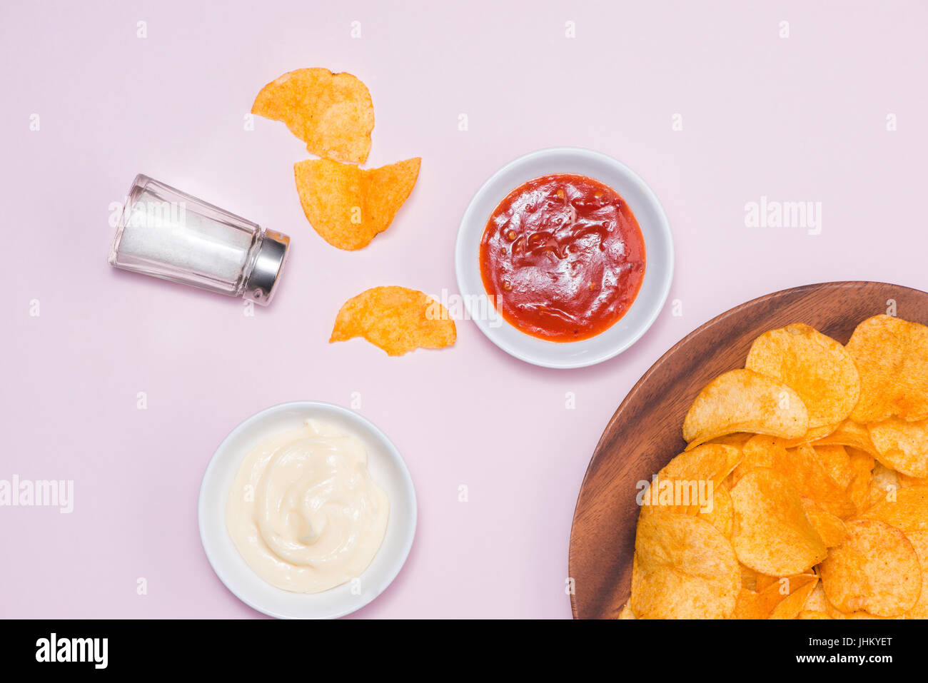 Konzept für ungesunde Lebensmittel. Käse und Zwiebel-Kartoffel-Chips mit hot Chilisauce auf rosa Hintergrund. Stockfoto