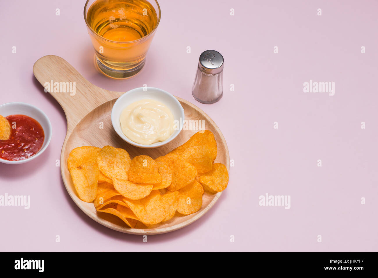 Konzept für ungesunde Lebensmittel. Käse und Zwiebel-Kartoffel-Chips mit hot Chilisauce auf rosa Hintergrund. Stockfoto