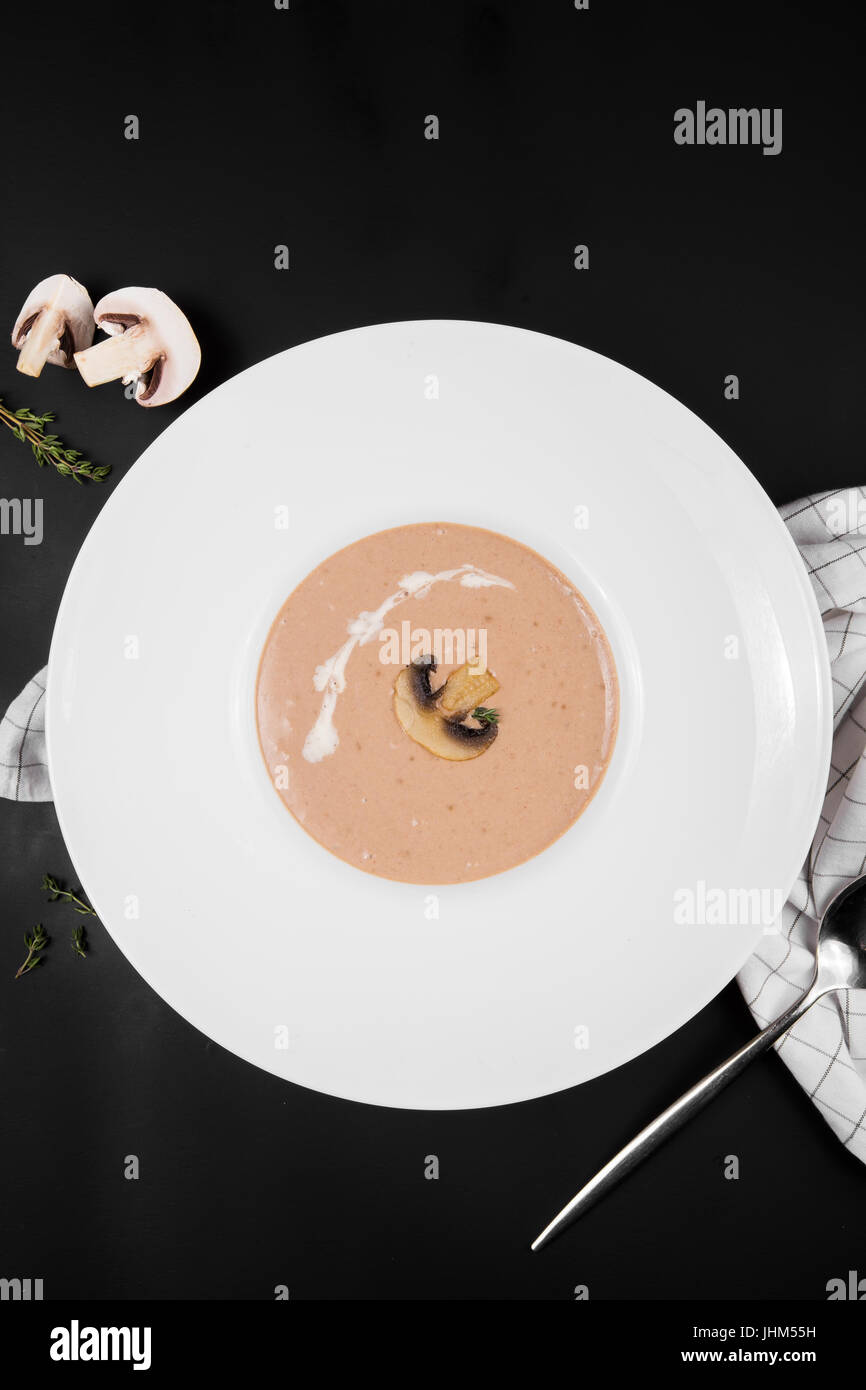 Champignon Cremesuppe in einer weißen Schüssel mit Würze auf schwarzem Hintergrund, Ansicht von oben Stockfoto