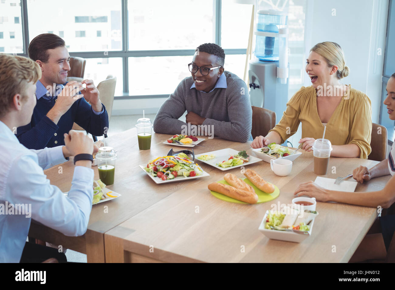 Glücklich Geschäftskollegen mit Mittagessen auf dem Tisch im Büro cafeteria Stockfoto