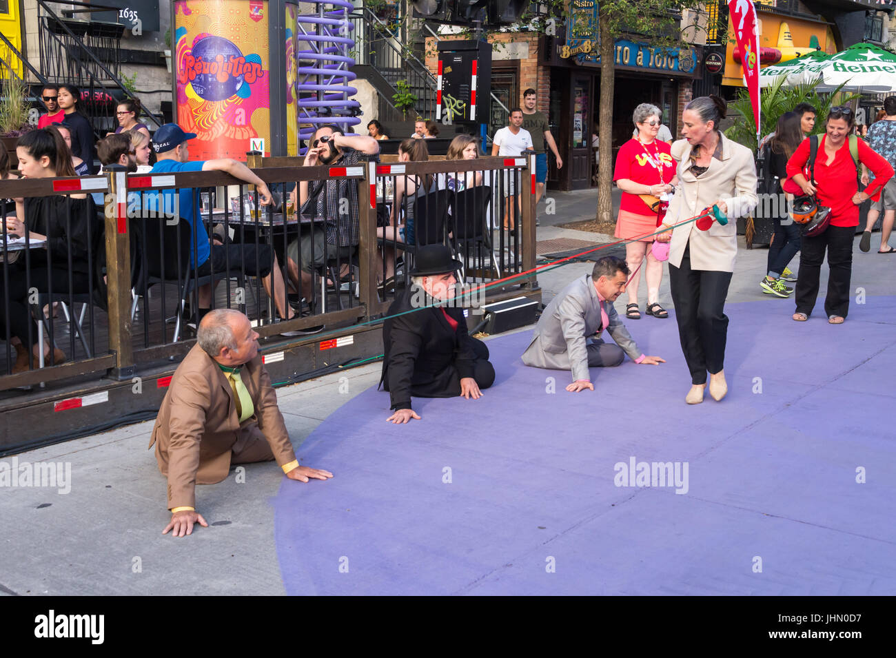 Montreal, Kanada - 13. Juli 2017: Frau zu Fuß drei Männer auf Hundeleinen im Circus-Festival von Montreal Stockfoto