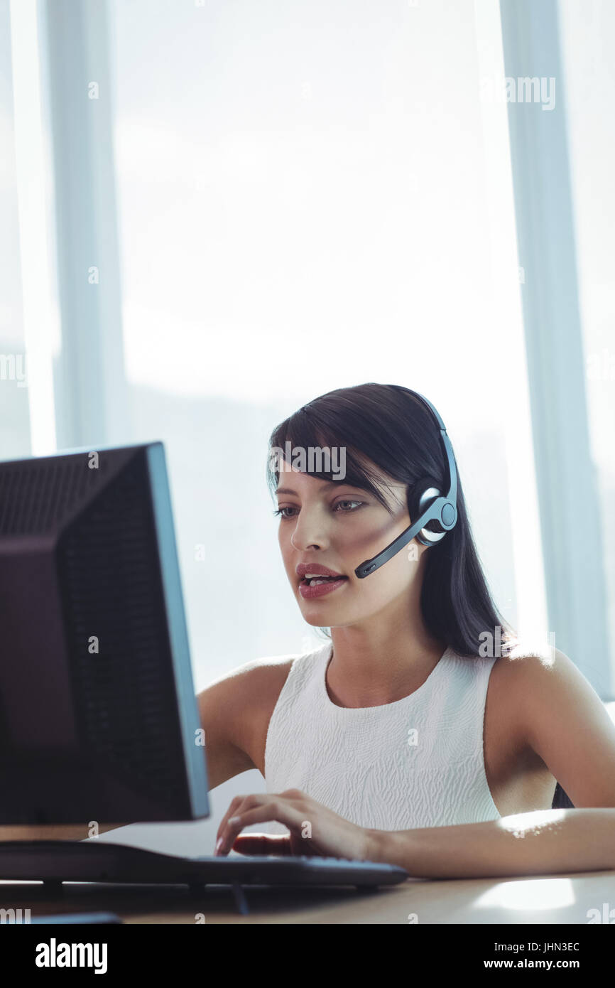 Junge Geschäftsfrau, reden über Kopfhörer während der Arbeit am Schreibtisch im Call-center Stockfoto
