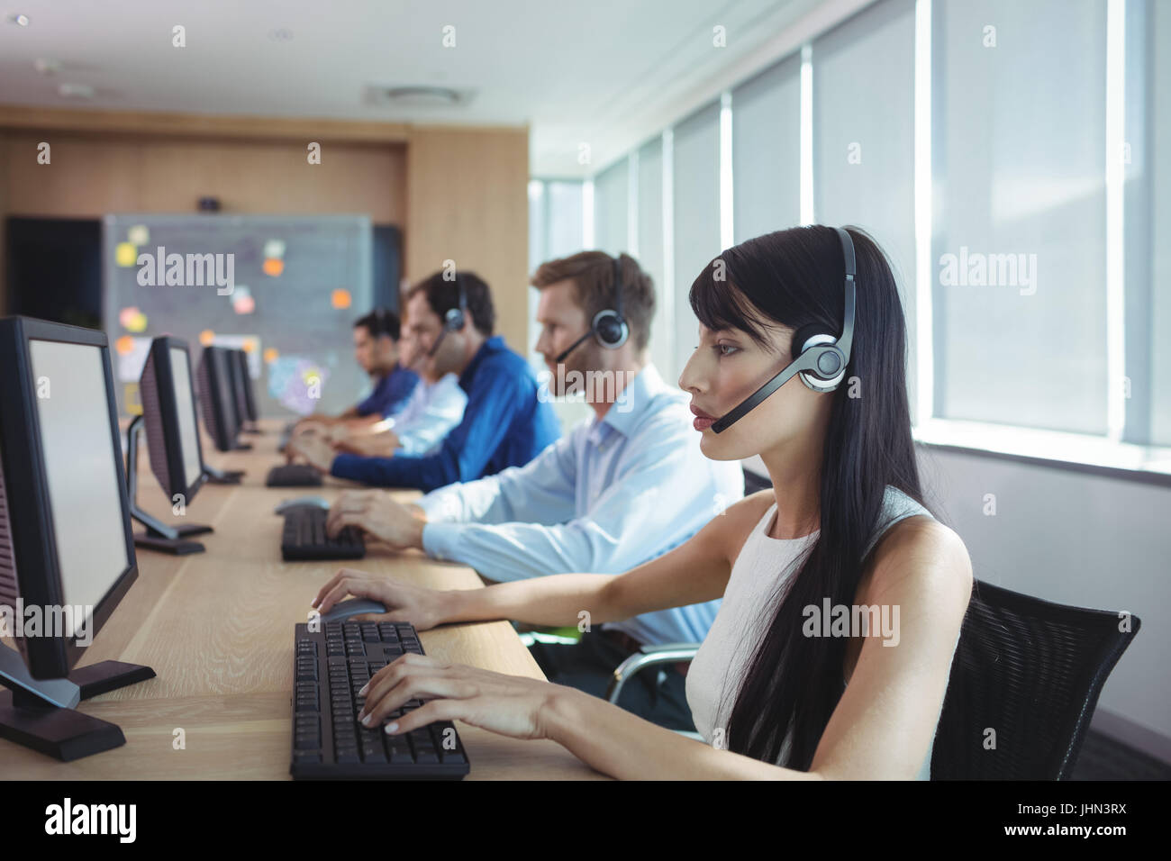 Geschäftsfrau, die Eingabe über Tastatur am Schreibtisch im Call-center Stockfoto