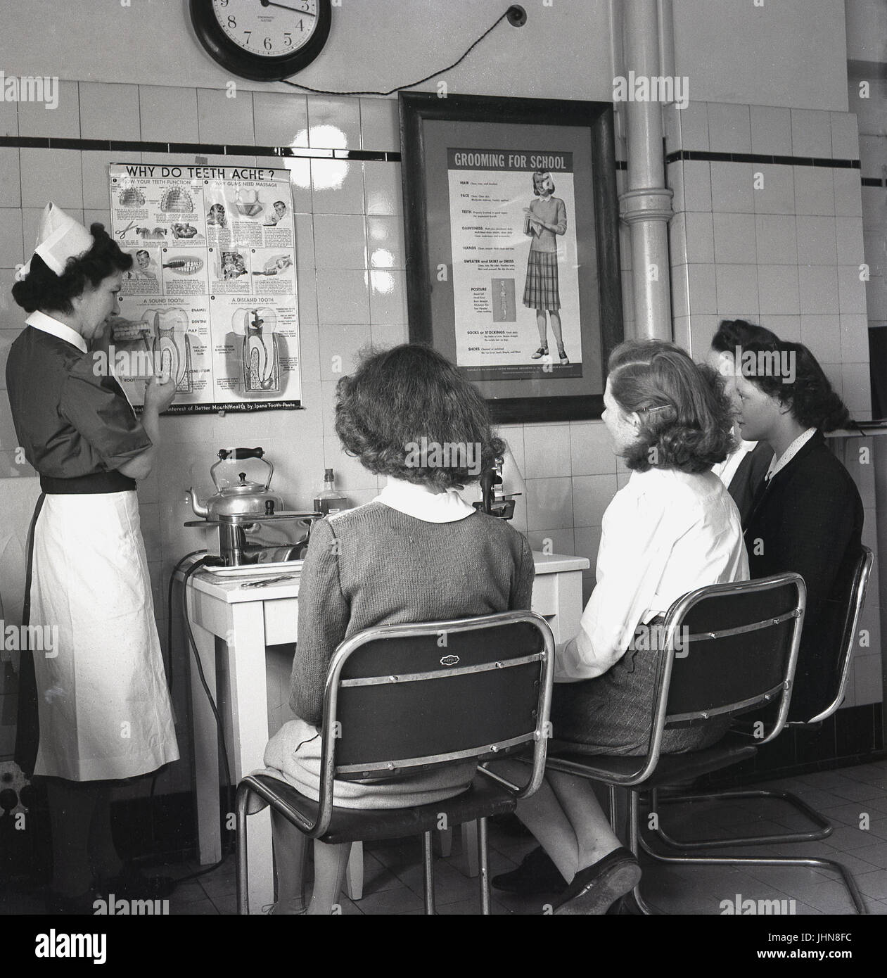 der 1950er Jahre, England, erläutern historische, vier weibliche Studenten eine Lehrerausbildung Hochschule hören Sie eine Krankenschwester Schule Schüler Zähne und wie Sie potenzielle Probleme zu identifizieren. Stockfoto