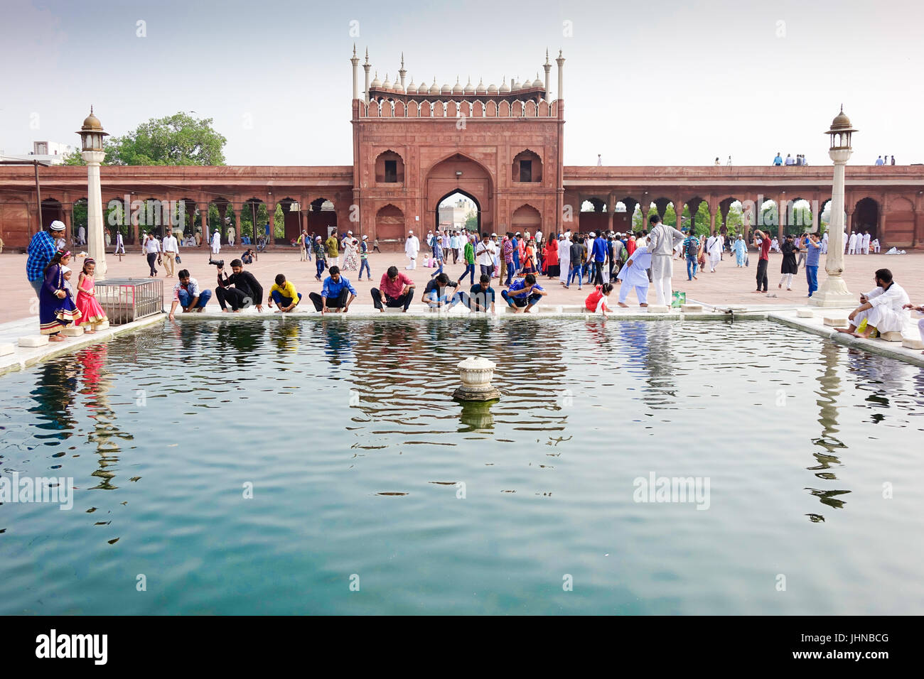 Menschen bei symmetrischen Architektur und heiligen islamischen Wasser Teich, d. h. Waschung Teich in Jama Masjid anlässlich des Eid al Fitr Stockfoto