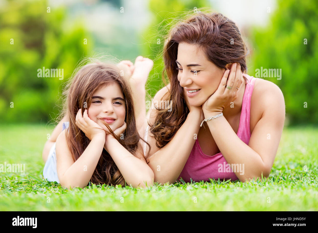 Porträt einer Mutter mit kleinen hübschen Tochter gemeinsam Spaß zu haben, die im Freien, liegend auf der Wiese, Entspannung in einer Landschaft, glückliches Familienleben Stockfoto