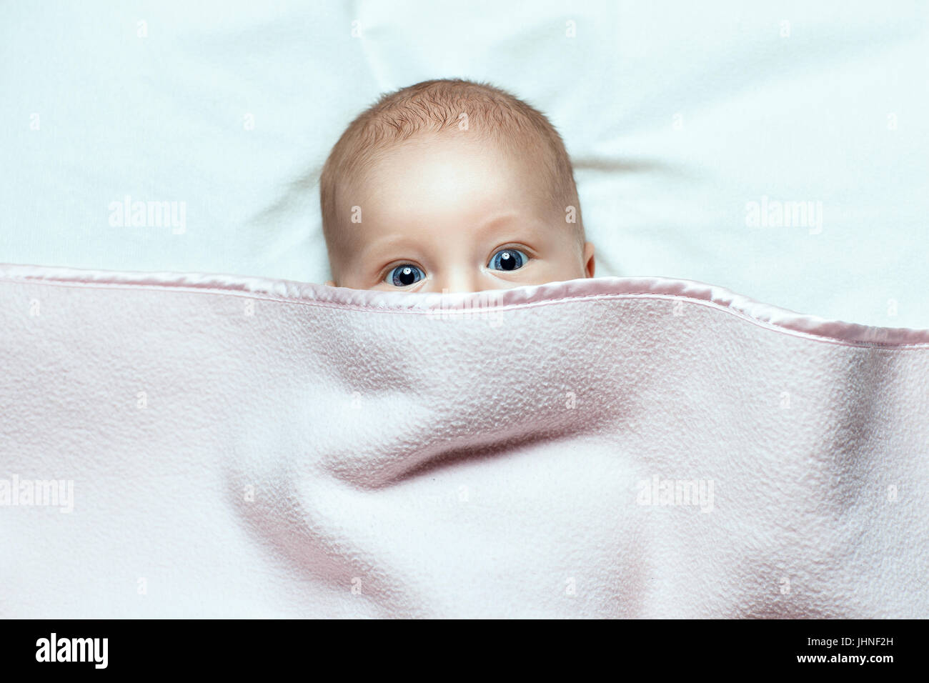 Babymädchen liegt. Sie ist mit einer Decke bedeckt. Stockfoto