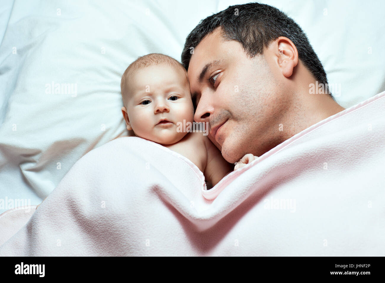 Vater und sein Babymädchen liegen unter einer Decke. Beobachtete Tochter Vater Stockfoto