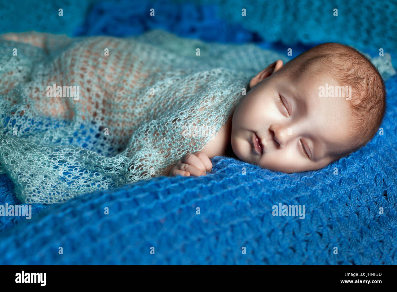 Baby Mädchen schläft. Sie ist mit einem blauen Strick Schal bedeckt. Stockfoto