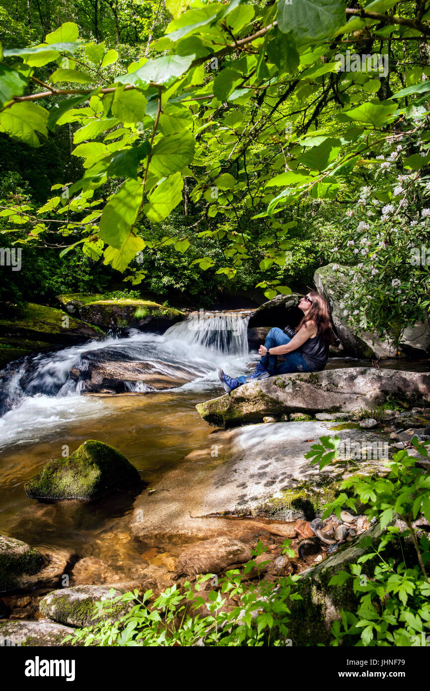 Junge Frau sitzt von Davidson River im Pisgah National Forest - nahe Brevard, North Carolina, USA Stockfoto
