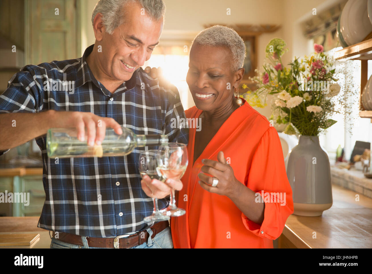 Lächelnde älteres paar strömenden Weißwein in Küche Stockfoto