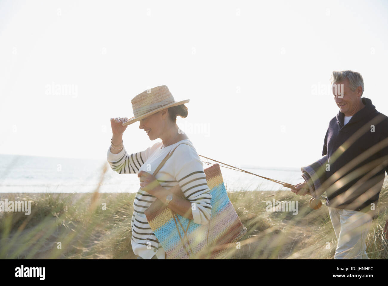Älteres Paar mit Angelrute Wandern im sonnigen Sommer Strandhafer Stockfoto