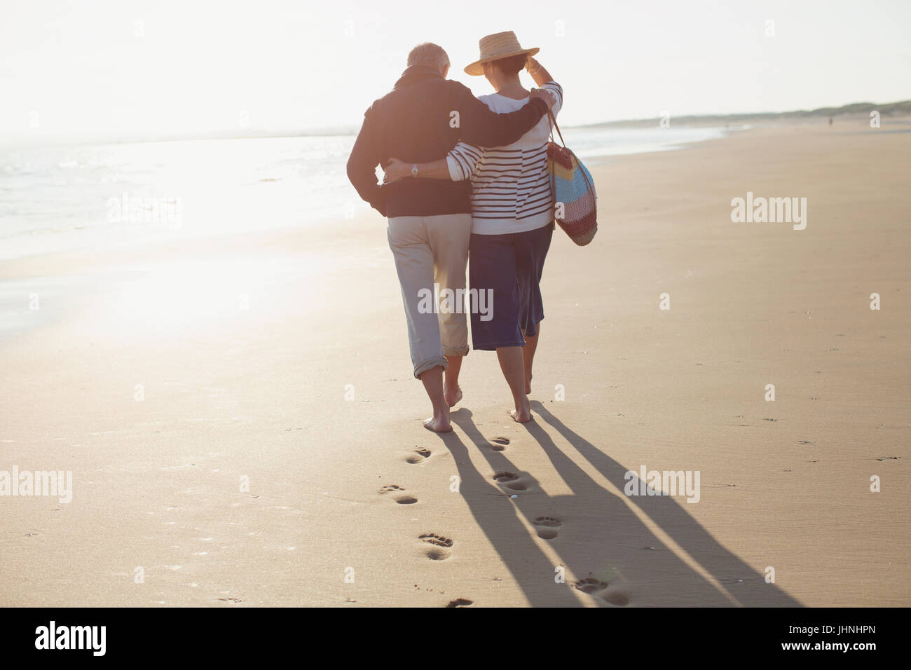 Älteres Paar zu umarmen und zu Fuß am Sonnenstrand Stockfoto
