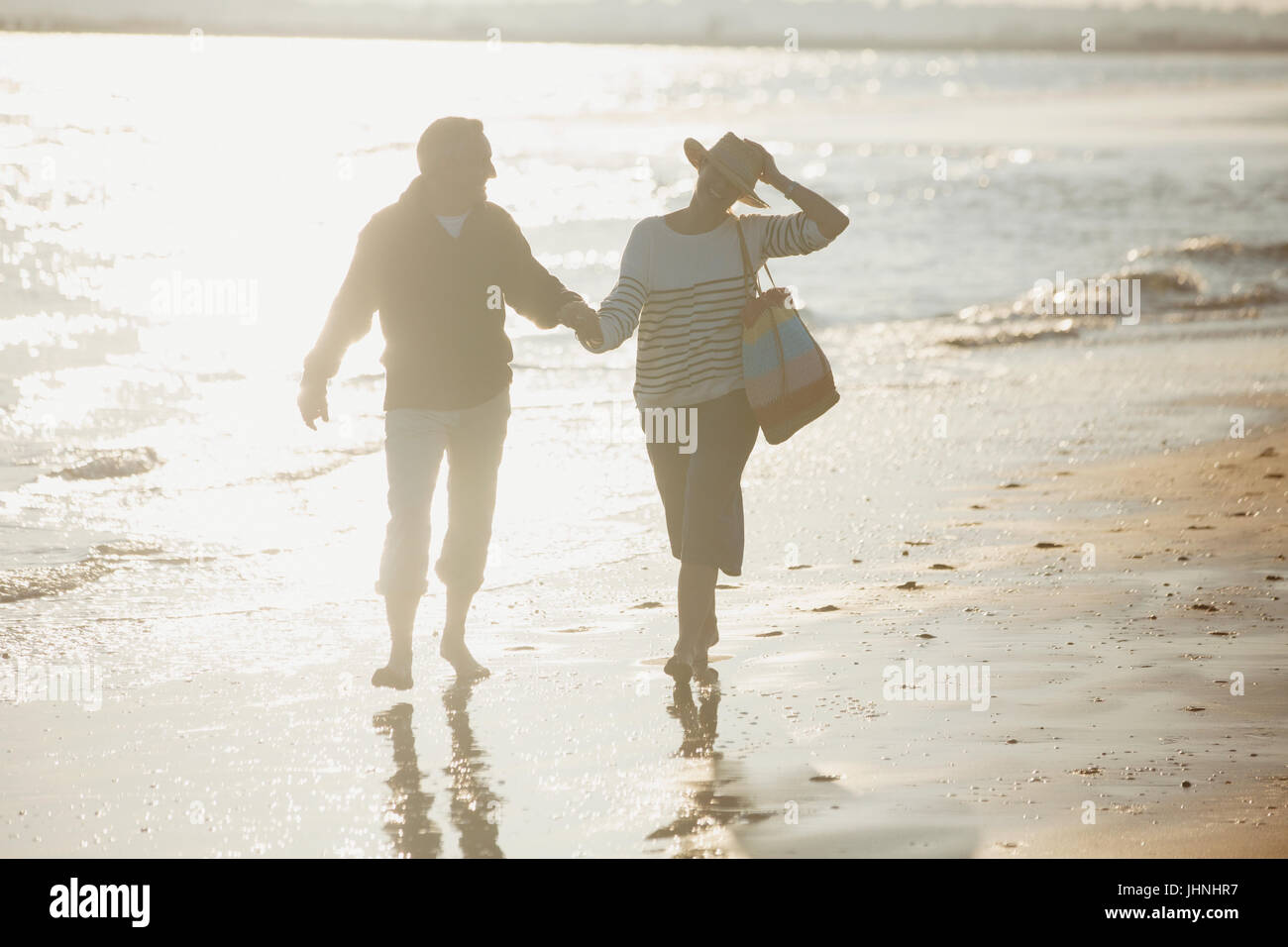 Älteres Paar Hand in Hand und Wandern am sonnigen Strand Stockfoto
