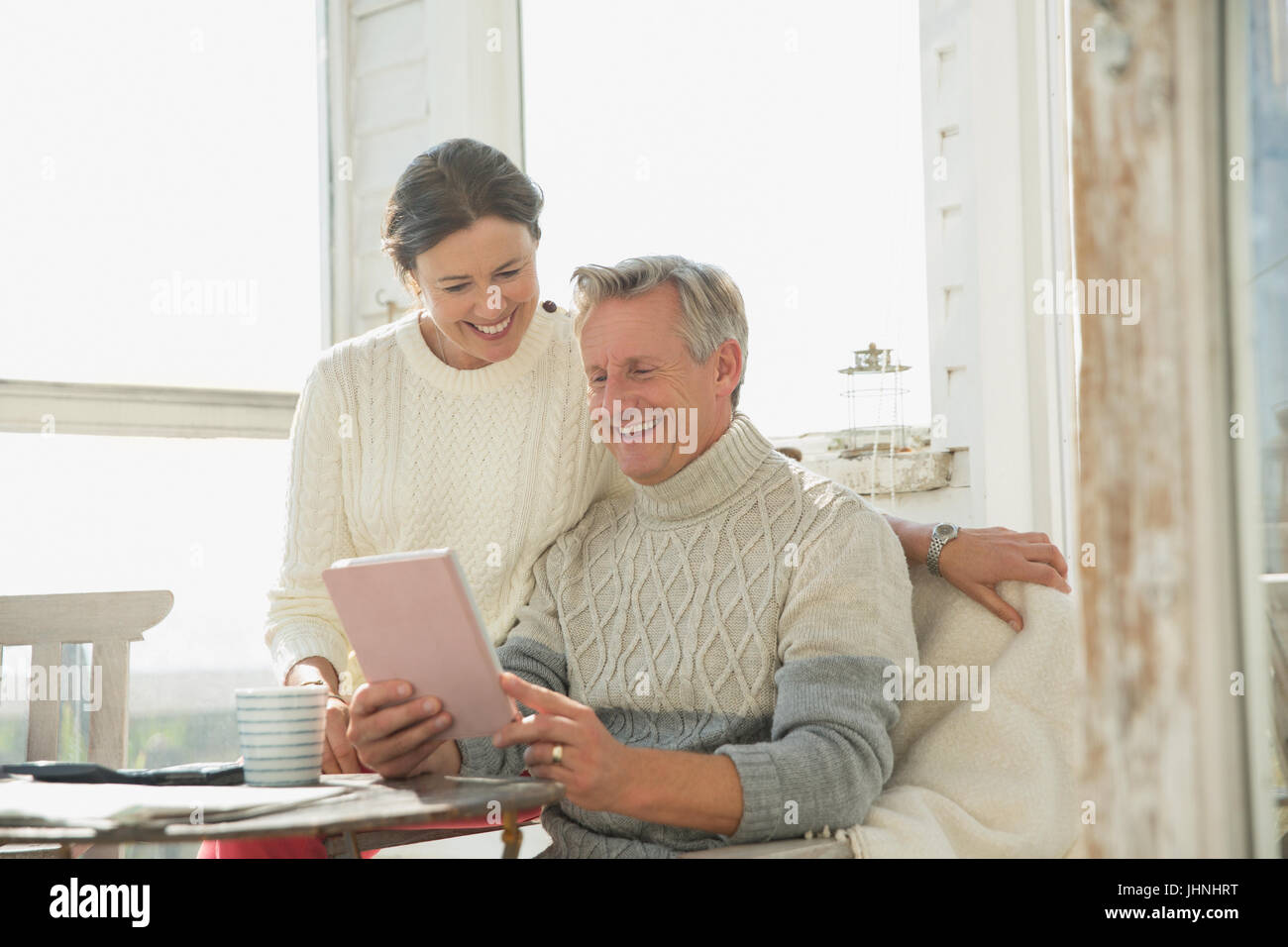 Älteres paar digital-Tablette am Tisch auf sonnige Veranda mit Lächeln Stockfoto