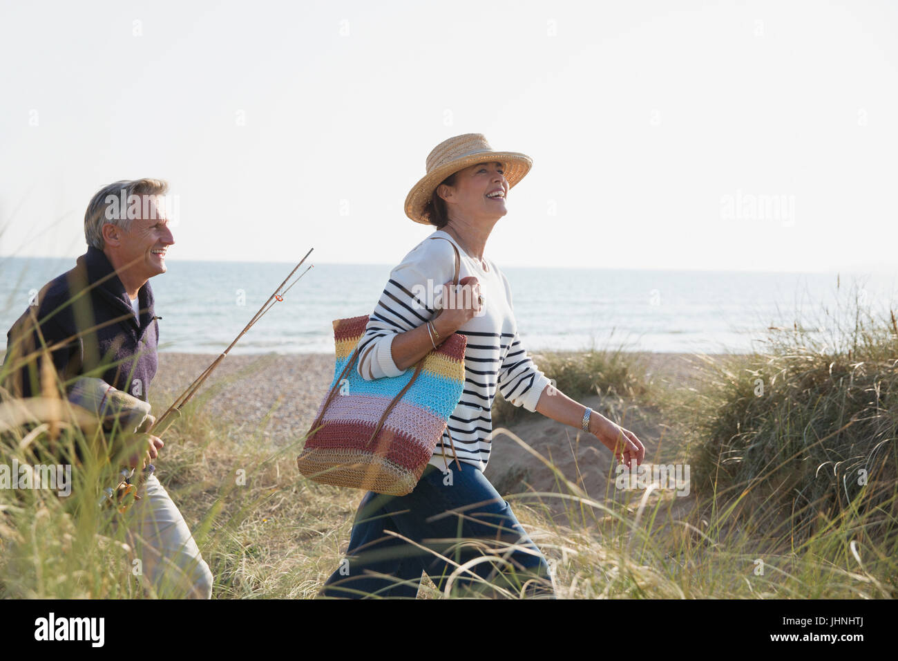 Älteres Paar mit Angelrute Wandern im sonnigen Strandhafer Stockfoto