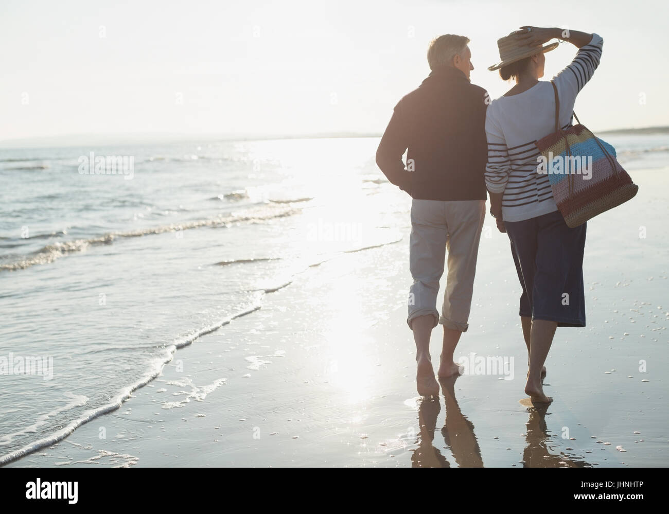 Älteres paar Wandern am sonnigen Ocean beach Stockfoto