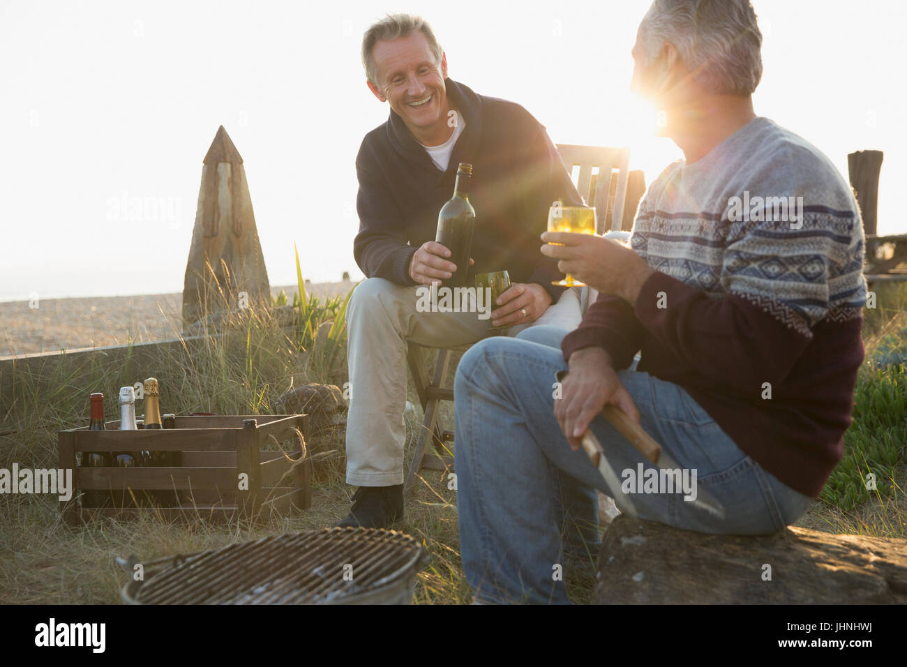 Senioren Herren Wein trinken und Grillen am Sonnenuntergang Strand Stockfoto