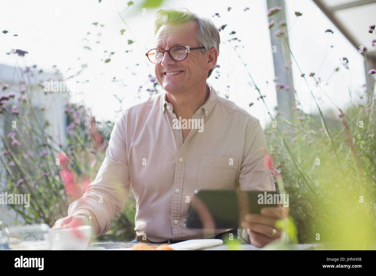 Lächelnder senior Mann mit digital-Tablette auf sonnigen Terrasse Stockfoto