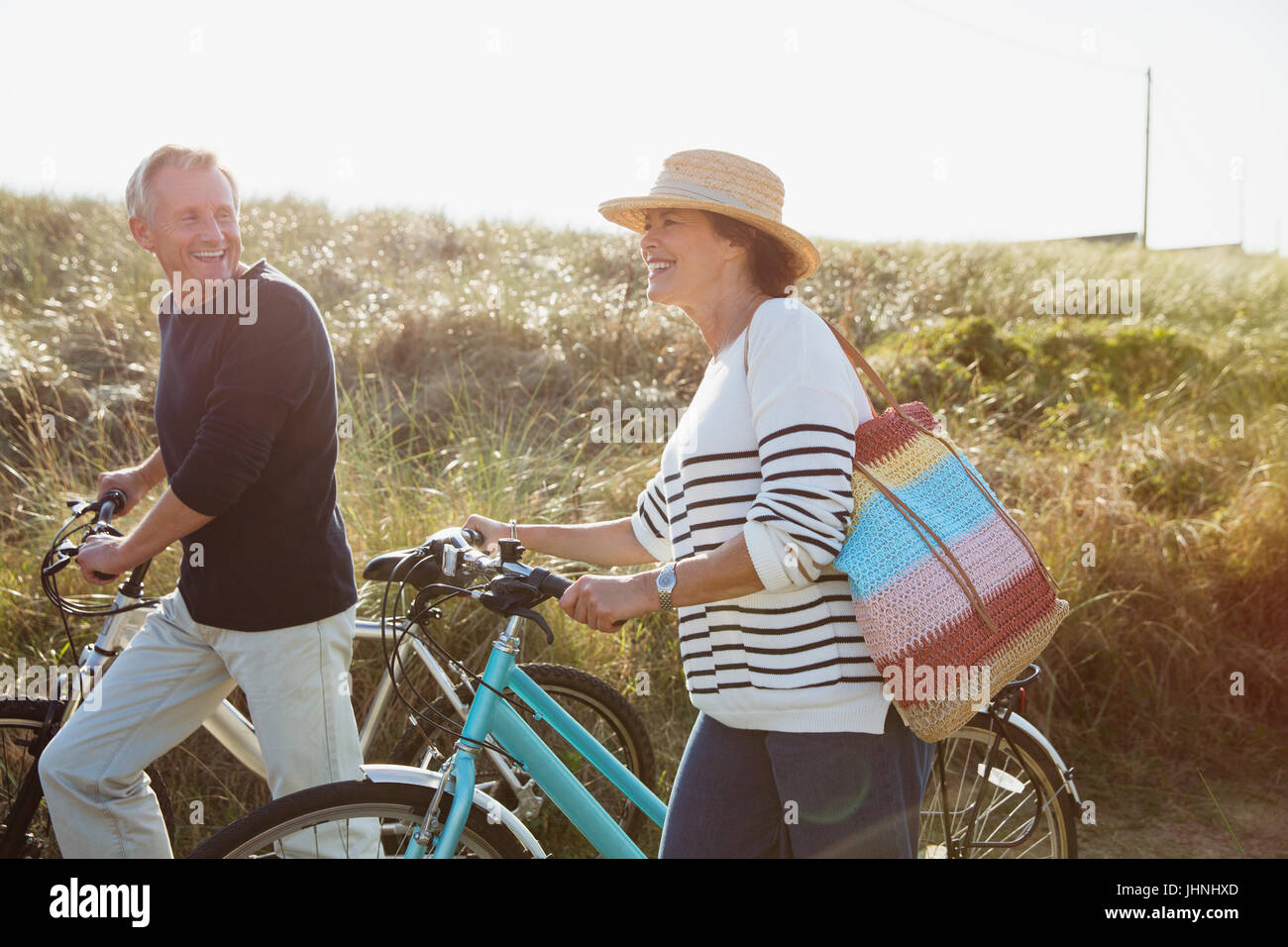 Älteres paar Fahrräder auf sonnigen Strandhafer Weg gehen Stockfoto