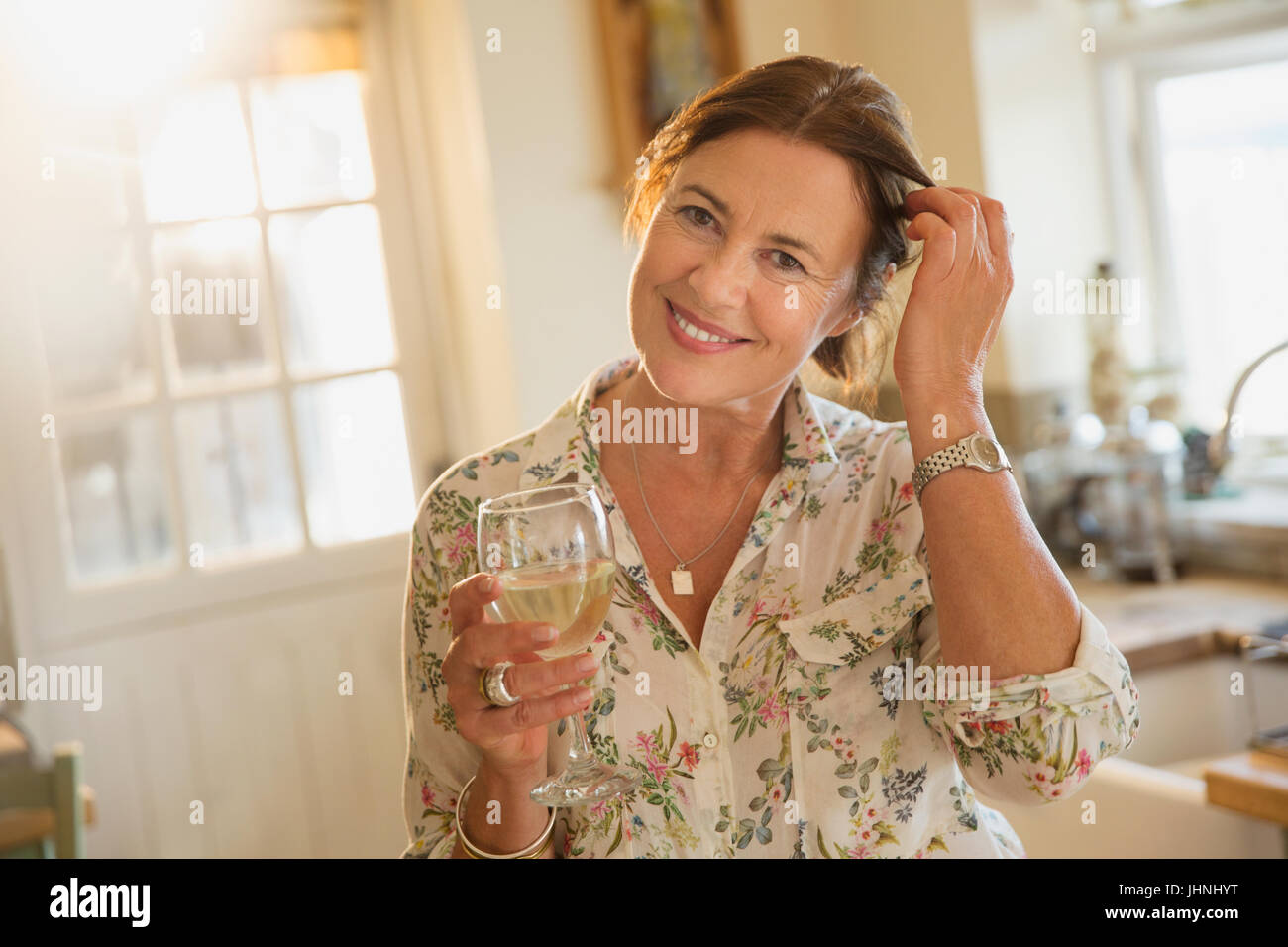 Porträt lächelnd Reife Frau trinken Weißwein in Küche Stockfoto