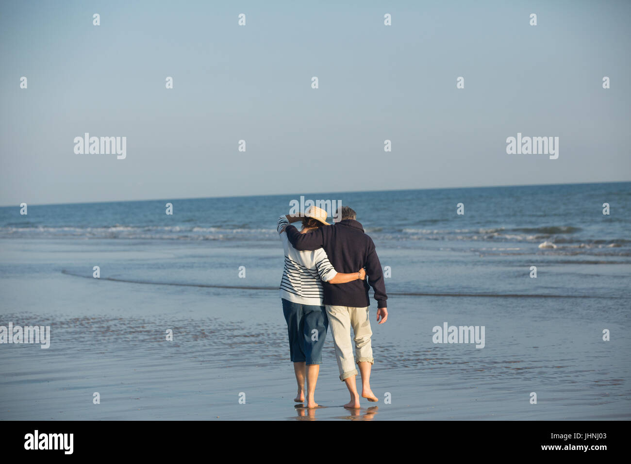 Liebevolle älteres paar umarmt, Wandern in sonnigen Strand-Brandung Stockfoto