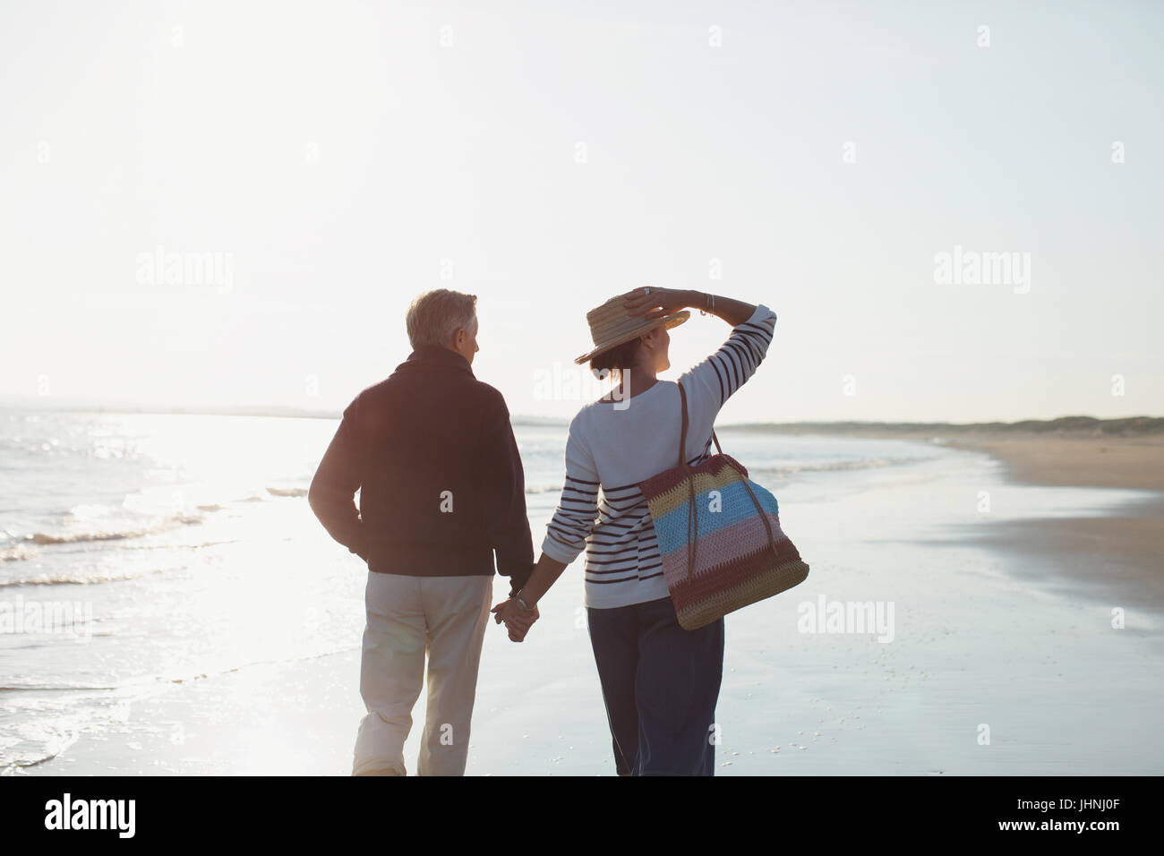 Liebevolle älteres paar Hand in Hand und Wandern am sonnigen Strand Stockfoto