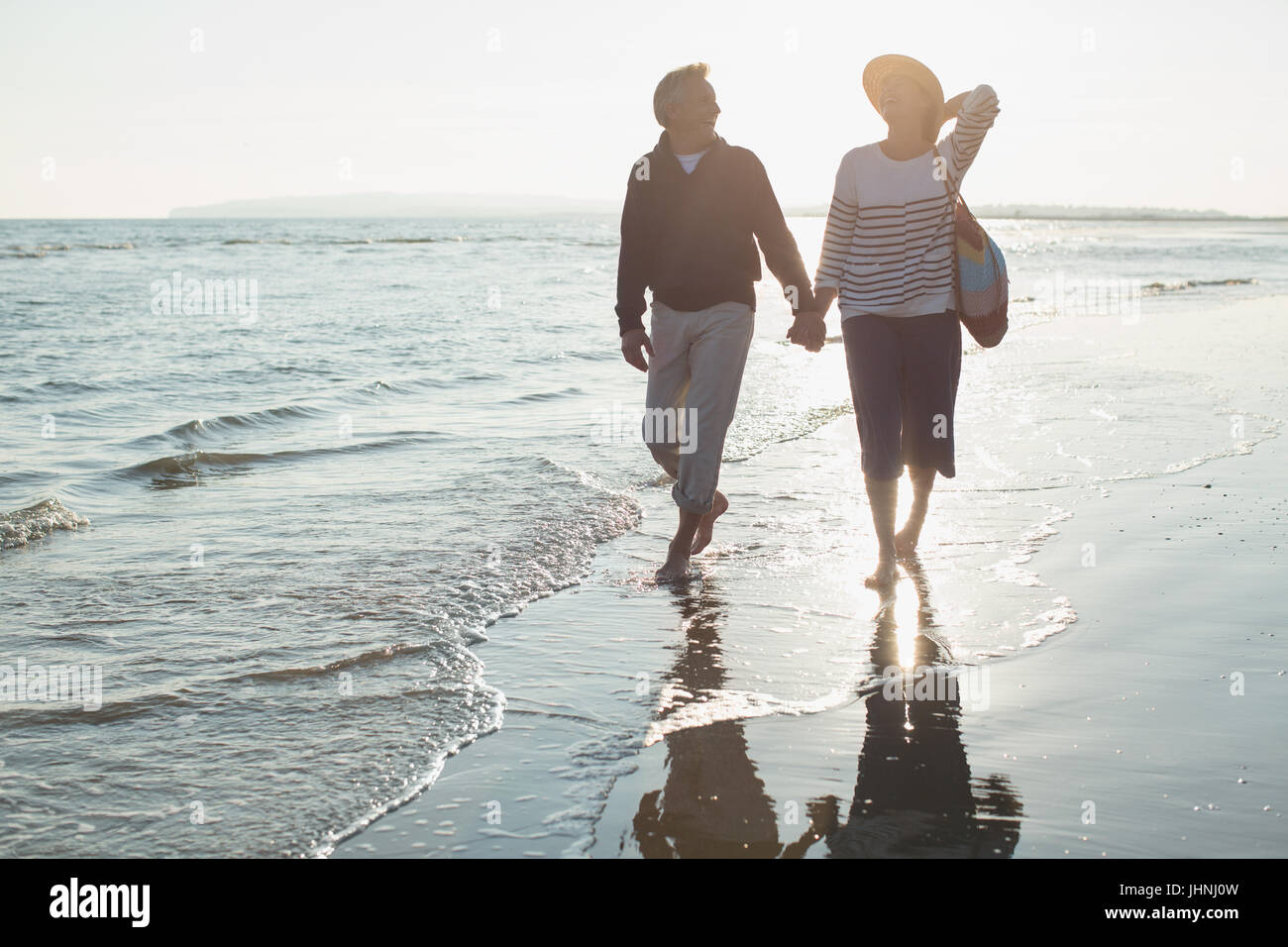 Liebevolle älteres paar Hand in Hand und Fuß am sunset Ocean Beach surfen Stockfoto
