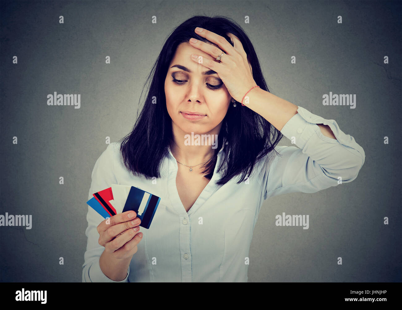 Betonte Frau Schulden mehrere Kreditkarten auf grauem Hintergrund isoliert betrachten Stockfoto