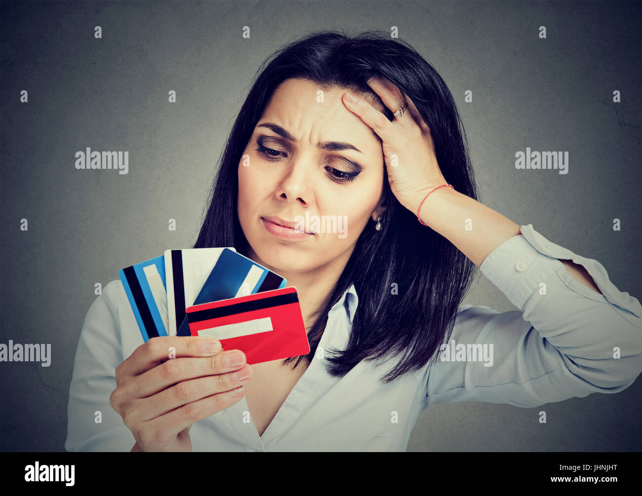 Betonte Frau Schulden bei mehreren Kreditkarten auf grauem Hintergrund isoliert Stockfoto
