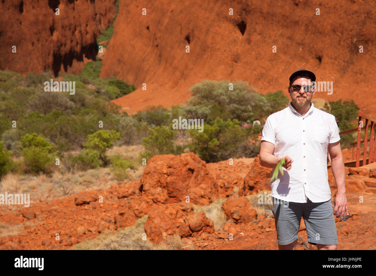 Kata Tjuta in der späten Nachmittagssonne, klaren, blauen Himmel, rot, trocken, Wüste Landschaft, mit grünen Büschen, Bäumen und Steinen, horizontale Aspekt. Stockfoto