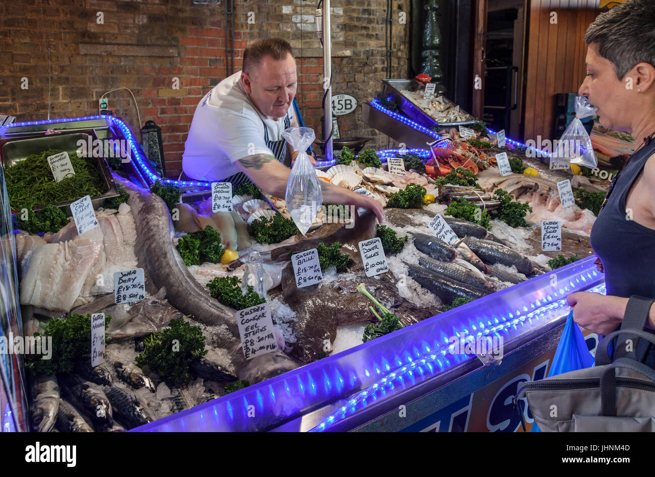 Standbesitzer und Kunden einen Fisch stall im Borough Market, dem historischen Lebensmittelmarkt in Southwark, zentrales London, England, UK Stockfoto