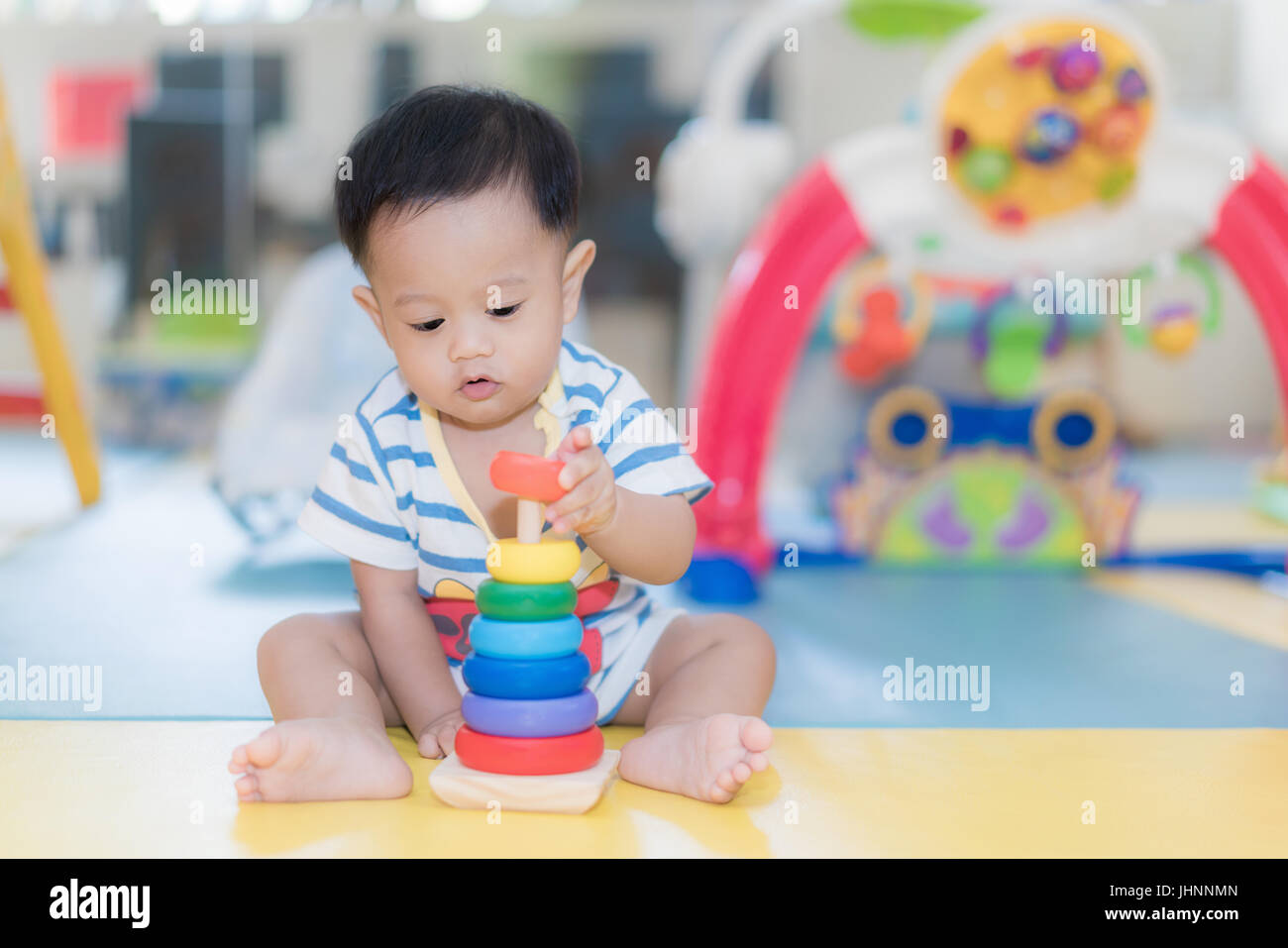 Entzückende asiatische Baby junge 9 Monate sitzen und spielen mit Farbe Entwicklungsstörungen Spielsachen im Kinderzimmer zu Hause. Stockfoto