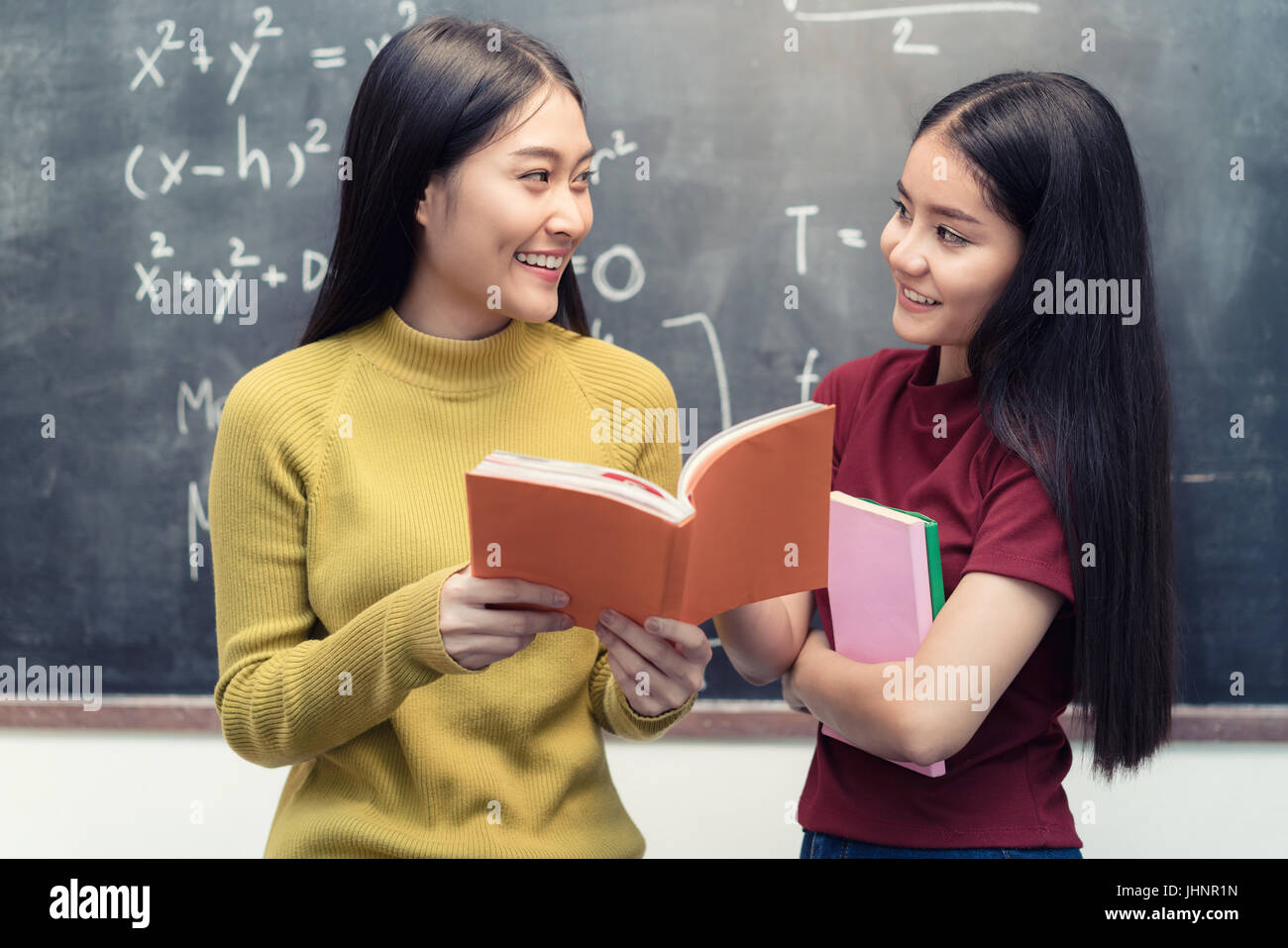 Asiatische Studentin über Tafel halten und lesen Bücher Togetherin Unterricht an der Universität. Bildungskonzept. Stockfoto