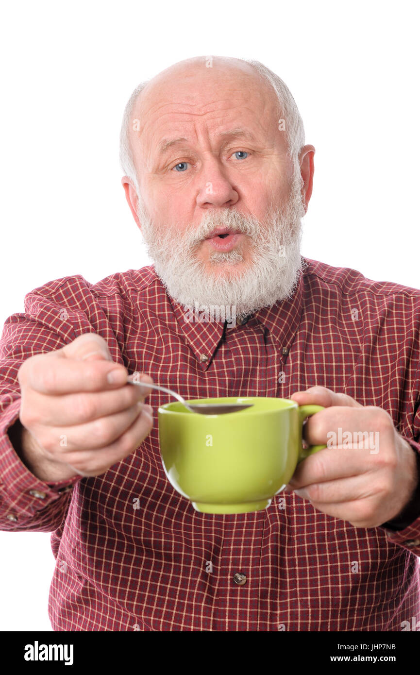 Unbekümmerte senior Mann mit grünen Tasse und Teelöffel, isoliert auf weiss Stockfoto