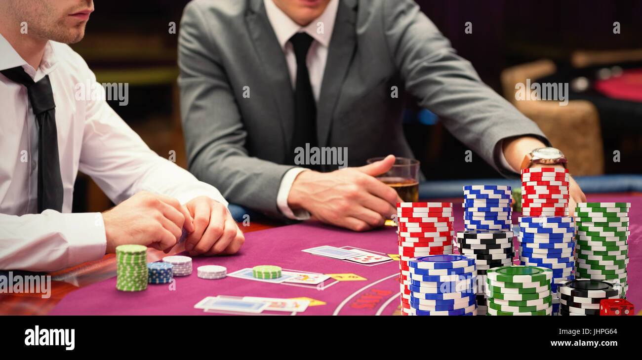 Stapel von bunten Casino Jetons mit roten Würfeln gegen Männer Wetten beim Pokerspiel Stockfoto