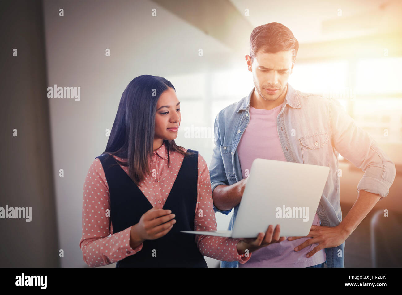 Geschäftskollegen mit Laptop gegen Whiteboard im Tagungsraum Stockfoto