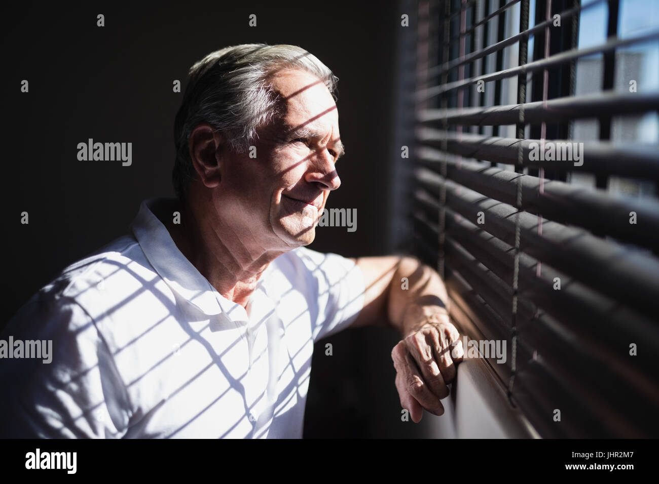 Nachdenklich senior männlichen Patienten Blick durch Fenster auf Krankenstation Stockfoto