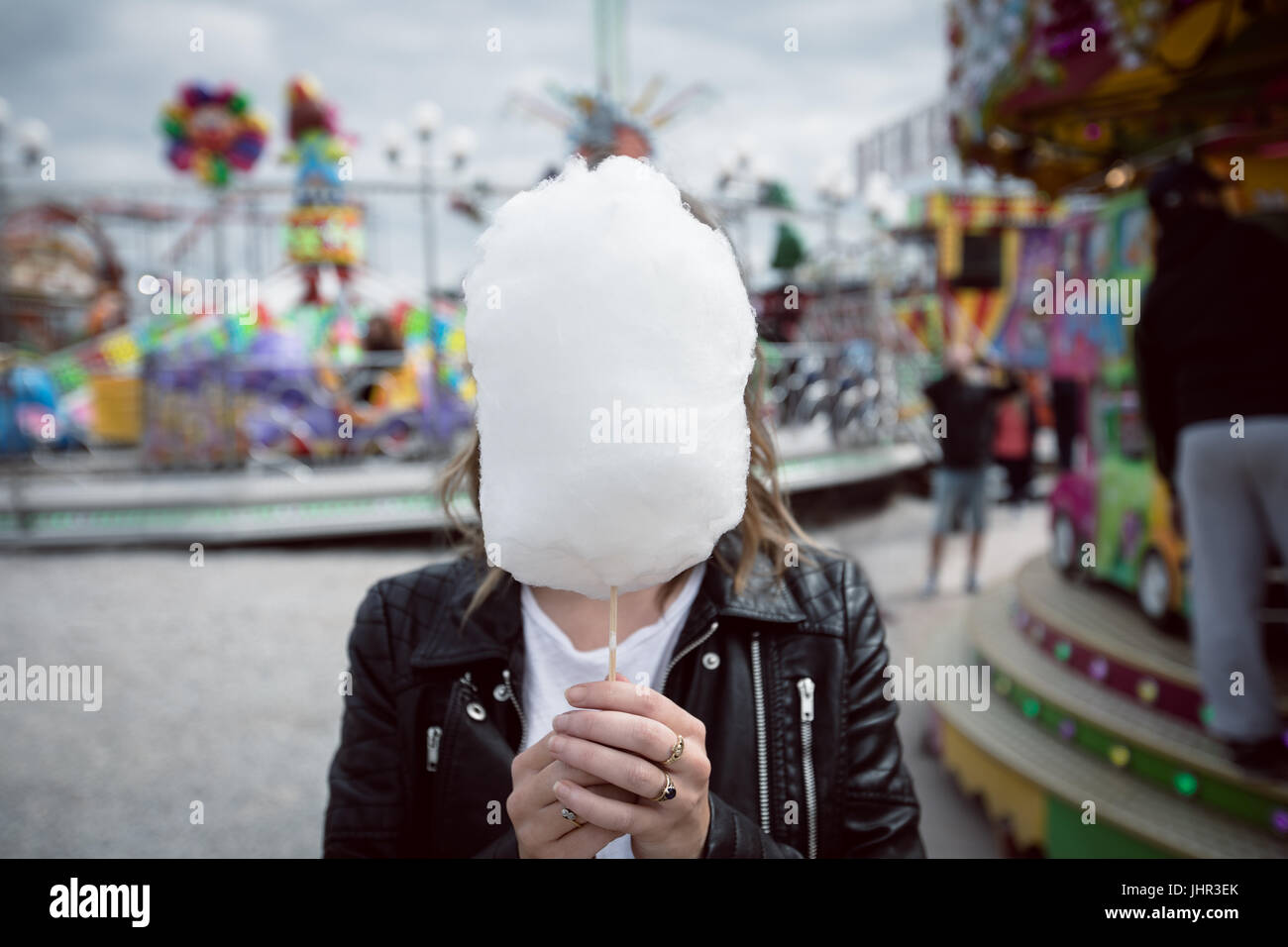 Frau verbirgt ihr Gesicht hinter Zuckerwatte im Vergnügungspark Stockfoto