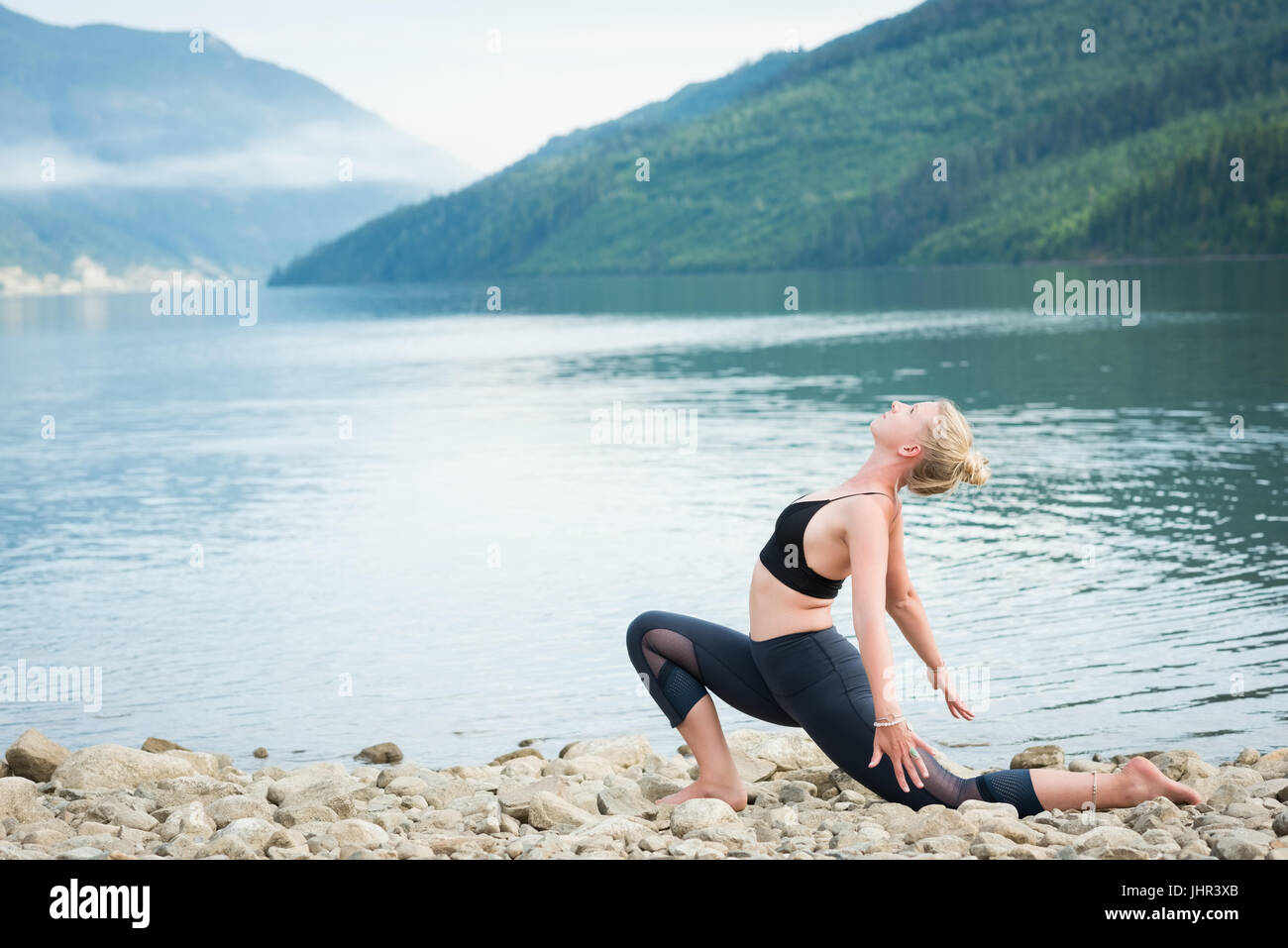 Seitenansicht der Frau praktizieren Yoga am Seeufer Stockfoto