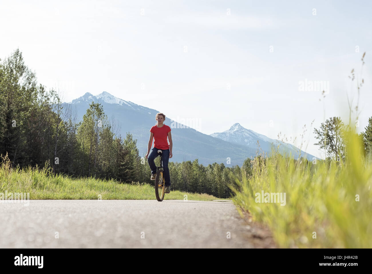 Ebene Oberflächenansicht von Frau Reiten Einrad unterwegs gegen Himmel Stockfoto