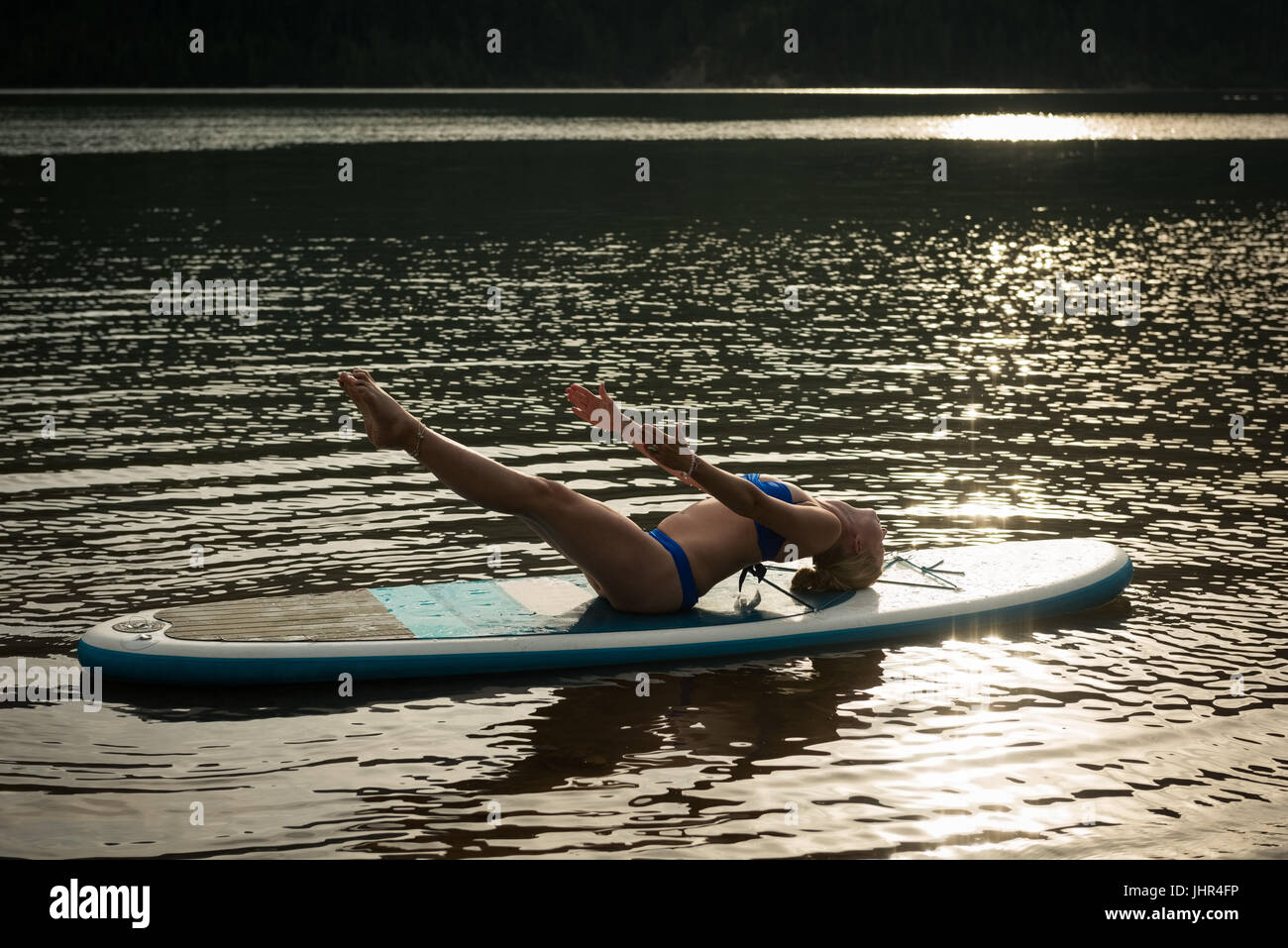 Seitenansicht der Frau praktizieren Yoga auf Paddleboard in See Stockfoto
