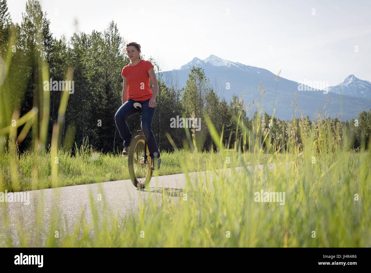 Ebene Oberflächenansicht von Frau Reiten Einrad unterwegs gegen Himmel Stockfoto