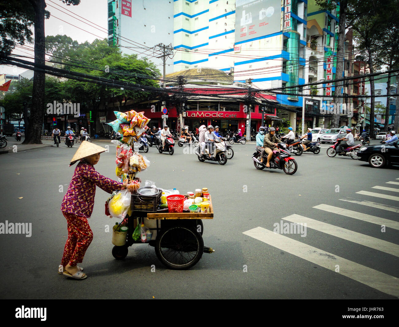 Streetfood Anbieter drängen ihren Warenkorb auf die belebte Straße überqueren Stockfoto
