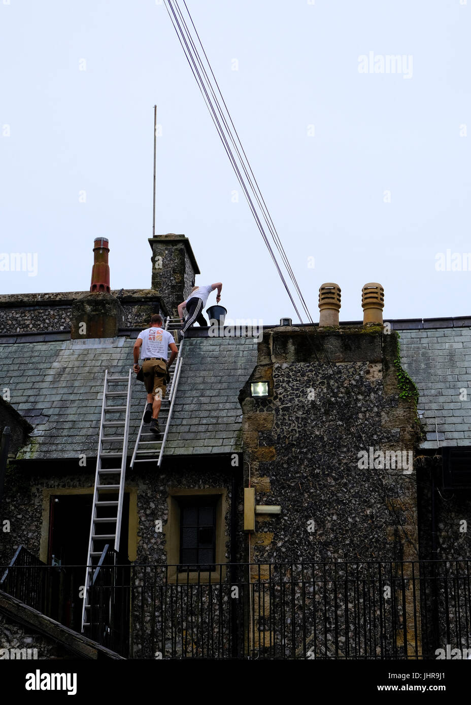 Zwei männliche Dachdecker Wartungsarbeiten arbeiten am Dach des denkmalgeschützten Gebäudes. Highdown Türme, Worthing, West Sussex, UK Stockfoto
